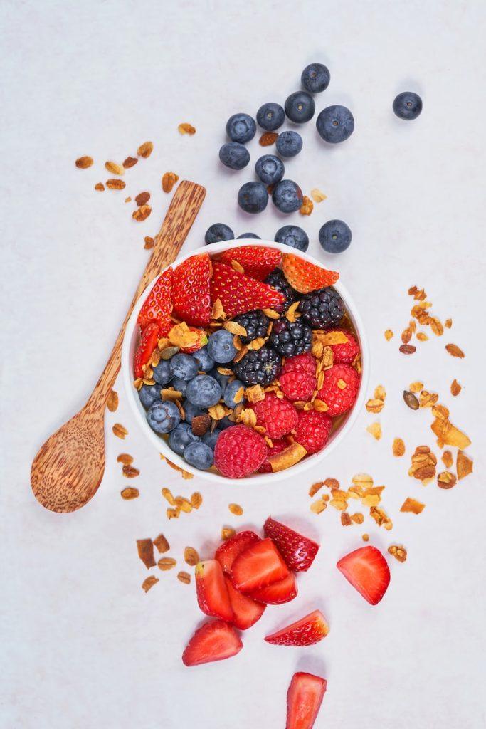 Red strawberries and blueberries on white ceramic bowl