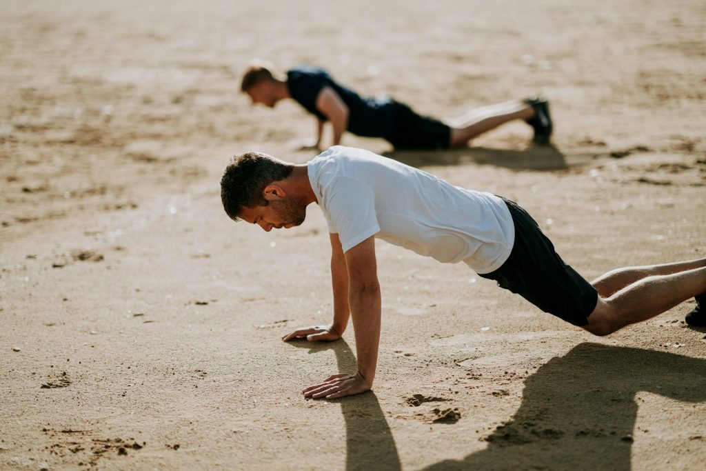 two men wearing black and white crew-neck t-shirts doing exercises called push-ups