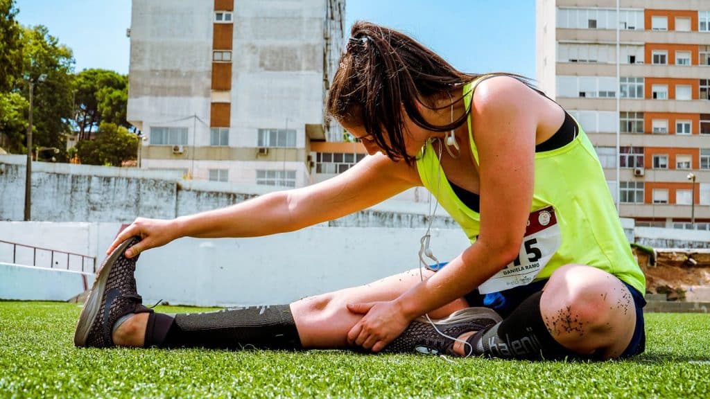 Women sitting and stretching on grass fields using cutting-edge diet and exercise strategies