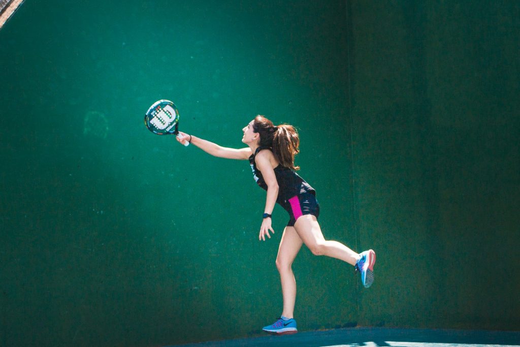 A woman holding a tennis racquet on a tennis court as she achieves her goals with a revolutionary diet and exercise regimen