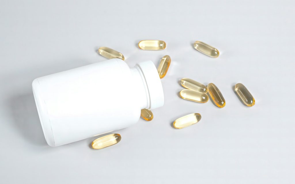 a white pill bottle knocked over with spilled vitamin supplements pills
