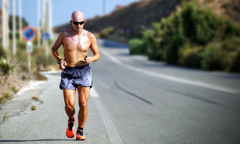 a lone runner in blue shorts jogging on a long stretch of highway