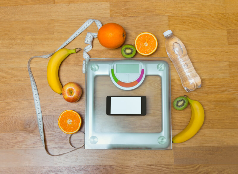 a smart scale surrounded by oranges, apples and bananas