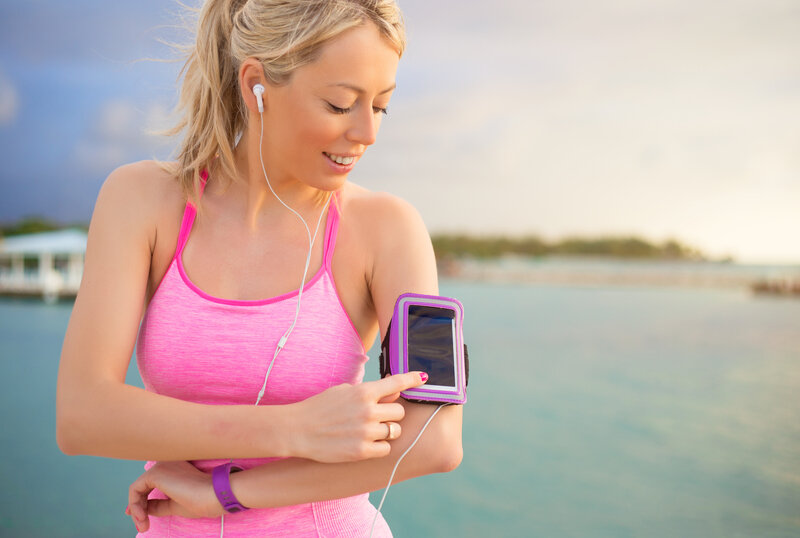 a woman wearing all pink exercise clothes tracking her progress on her mobile app