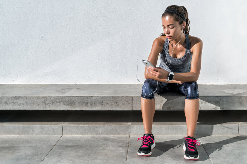 A woman sitting on a bench checking her simple diet and exercise program progress