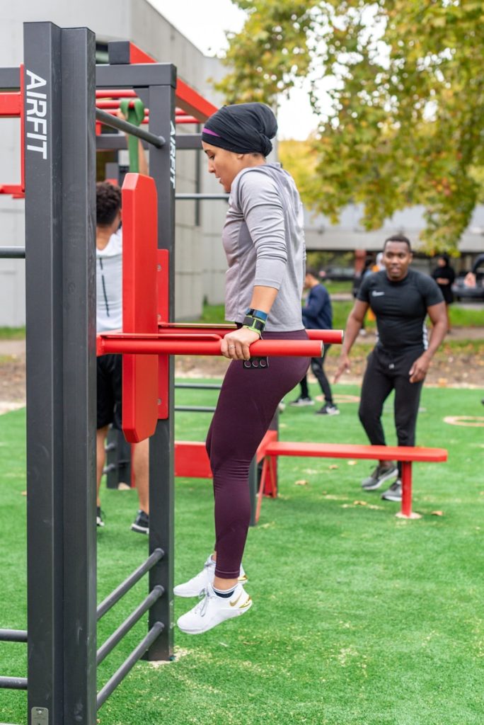woman in white long sleeve shirt and red pants standing on red metal bar showing how to lose weight and feel good doing it
