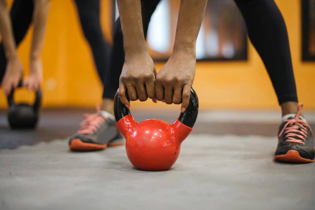 A person lifting a red kettlebell during a tailored diet and exercise plan
