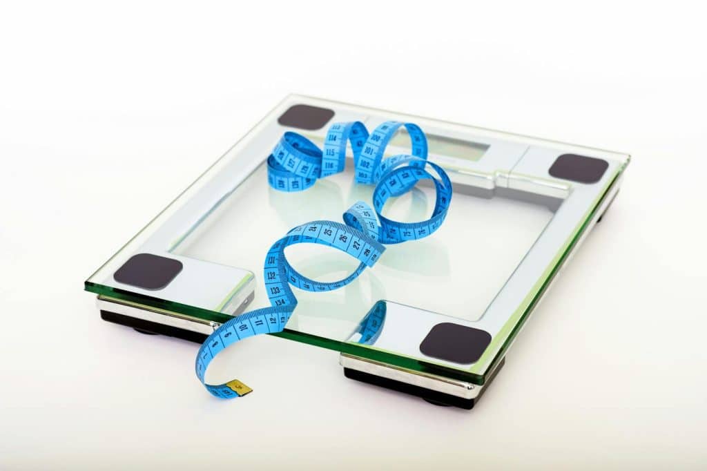 Blue tape measure on a clear glass square scale to transform your life with modern diet and exercise secrets